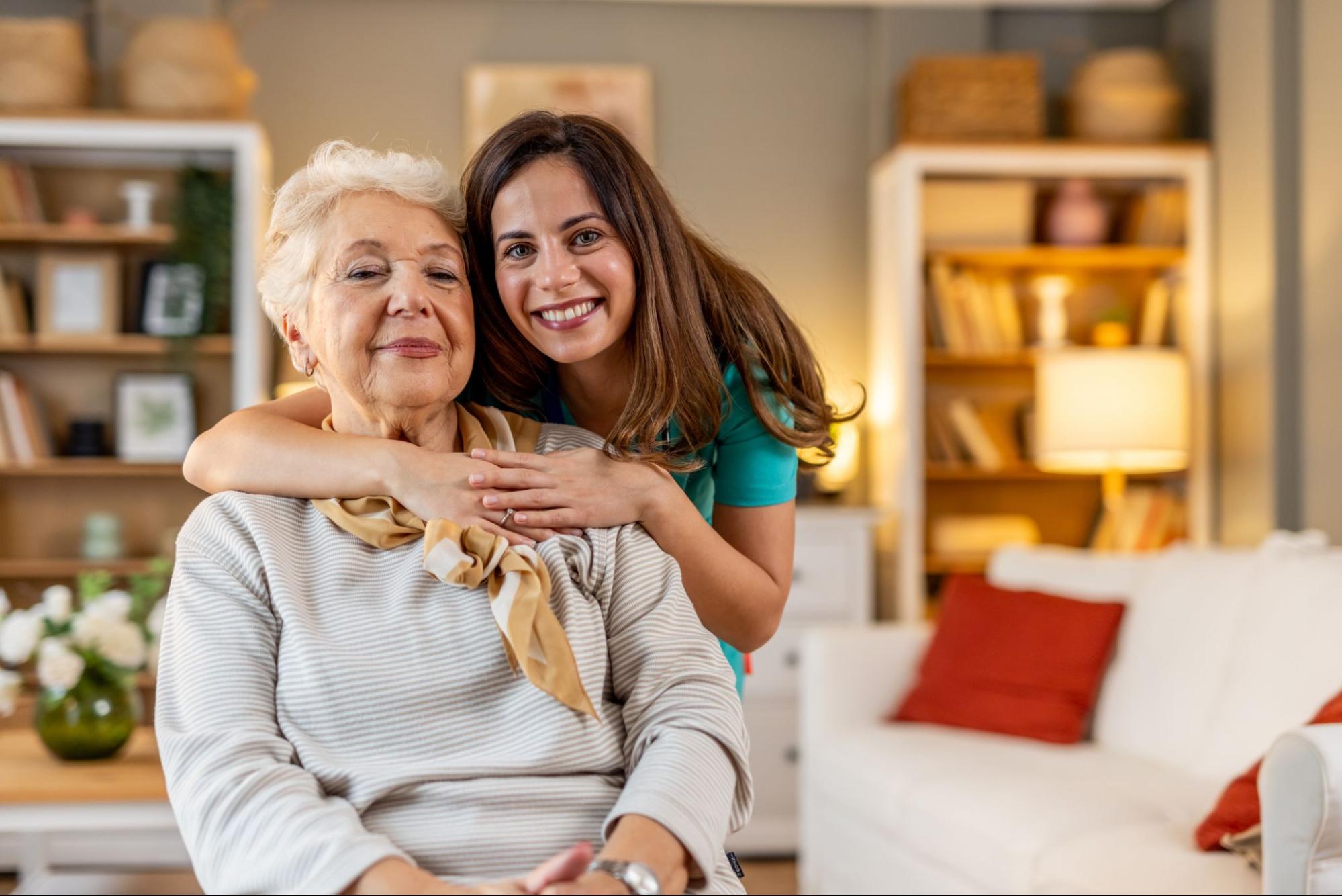 Smiling caregiver hugging an older woman at home during respite care in Maine